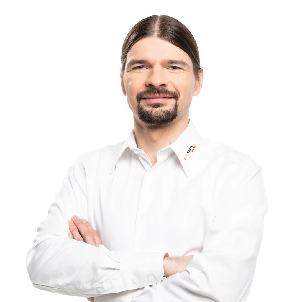 Porträt von Ralf Schwarzmaier, Geschäftsführer von Mars Solutions, im weißen Hemd mit Firmenlogo, vor weißem Hintergrund.